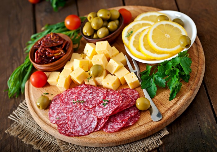 Sausage, Cheese, Olives, Lemons, and Tomatoes on a Cutting Board
