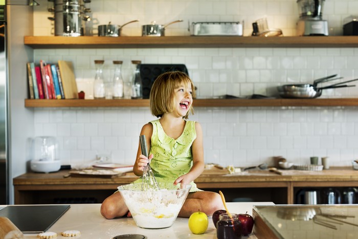 Little girl laughing while baking in a kitchen