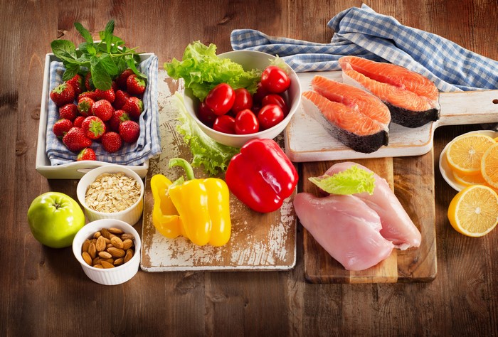 Still-life of healthy foods: salmon, chicken, fruits, vegetables, nuts, and oats