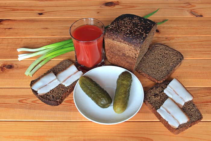 Salo, bread, pickles, tomato juice, and green onions on wood