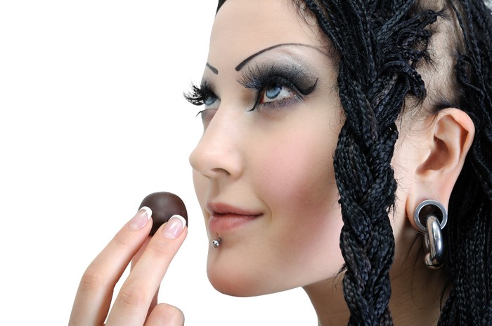 Woman with braids and body piercings holding a chocolate