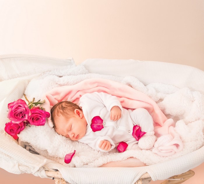 Newborn baby sleeping with roses and petals
