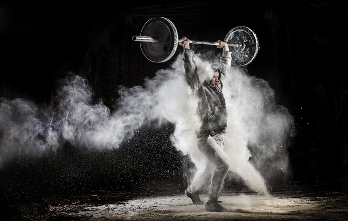 Man lifting barbell with white powder explosion