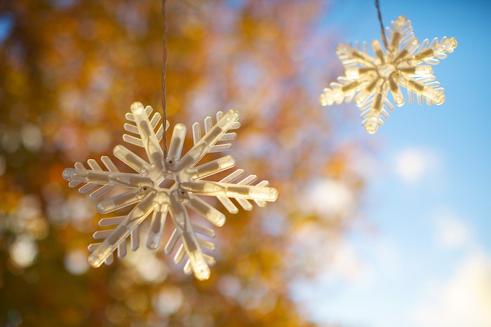 Snowflake fairy lights against autumn foliage and blue sky