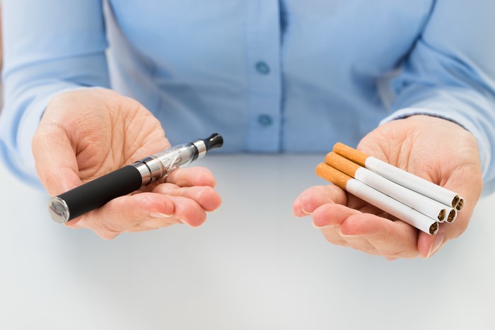 Hands holding an electronic cigarette and cigarettes