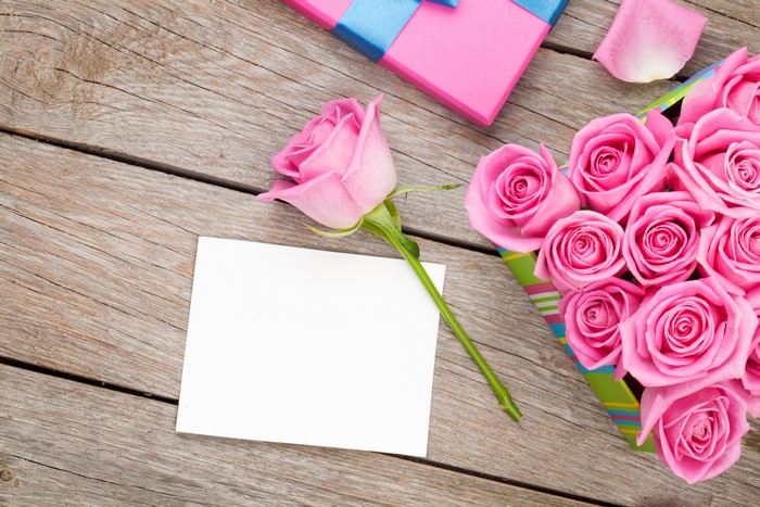 Pink roses and gift box on wooden planks