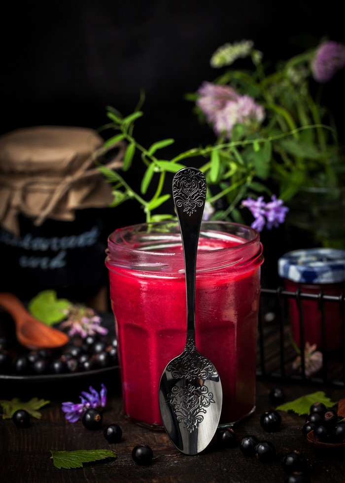 Jar of jam with black currants and spoon