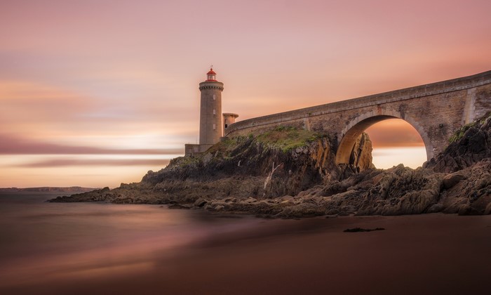 Lighthouse and bridge over rocky coast at sunset, Plouzane, France