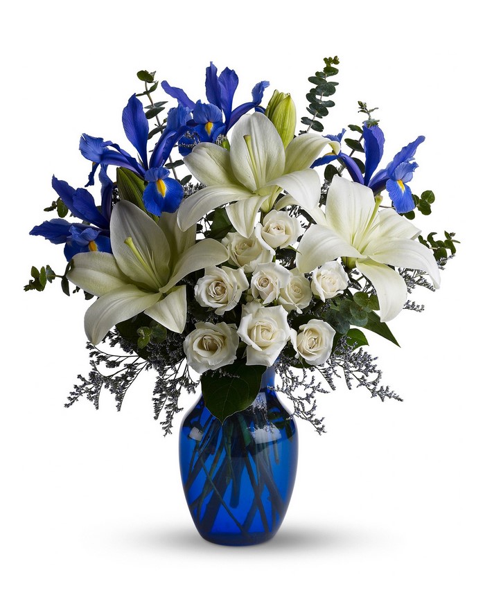 White lilies, roses, and blue irises in a blue vase