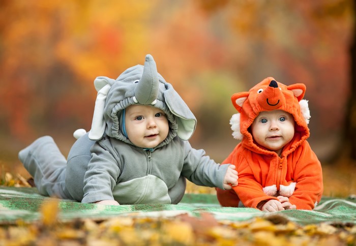 Two babies in animal costumes outdoors