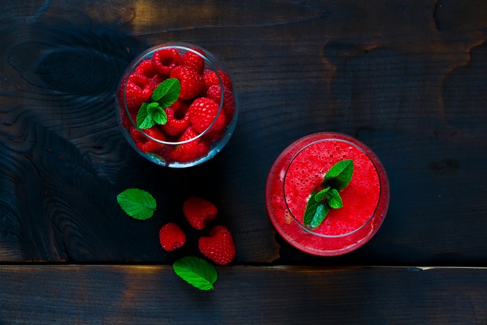 Raspberry smoothie and raspberries with mint on wood