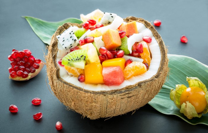 Fruit salad in a coconut bowl with pomegranate and physalis