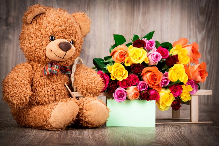 Teddy bear with colorful roses and greeting card