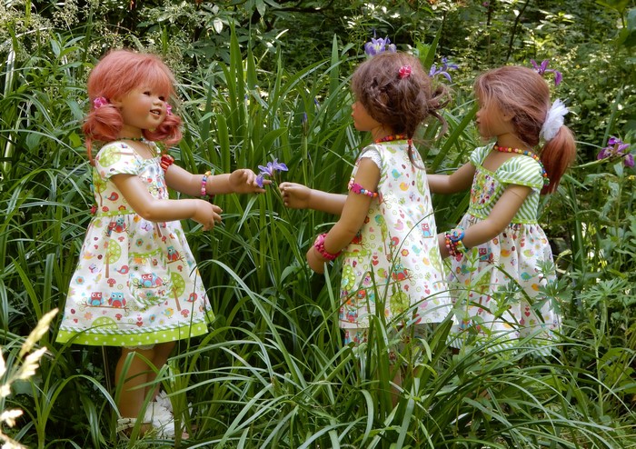 Three dolls in dresses in a park