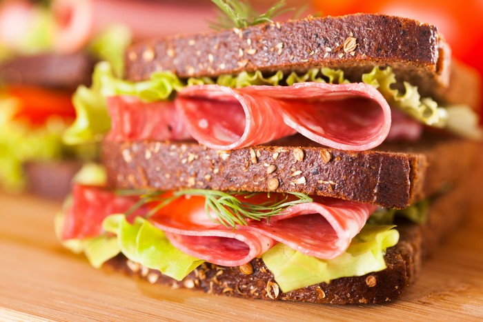 Sandwich with salami, lettuce, and dill on dark bread