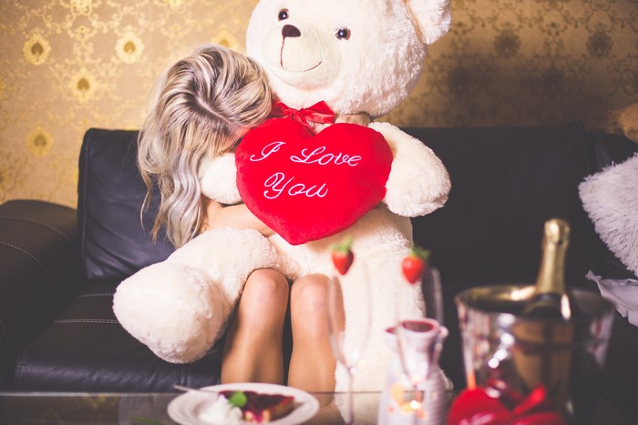 Woman hugging a teddy bear with a heart pillow