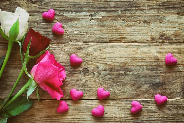 Roses and pink hearts on wooden background