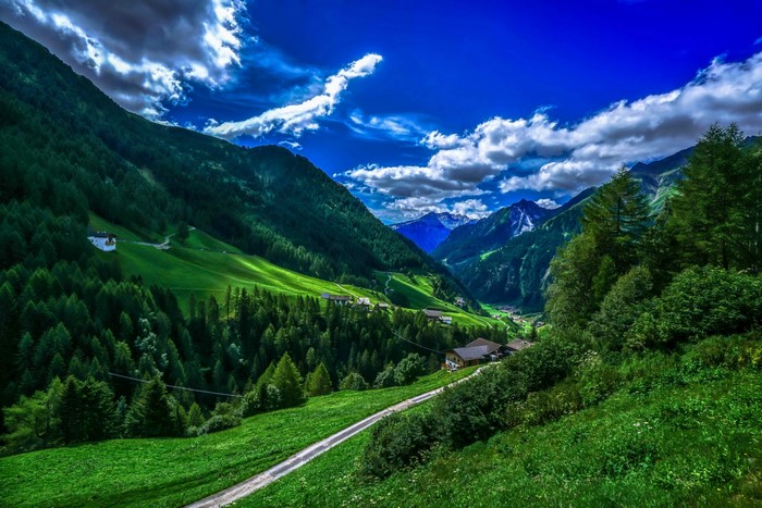 Mountain valley with green hills and forests under a blue sky
