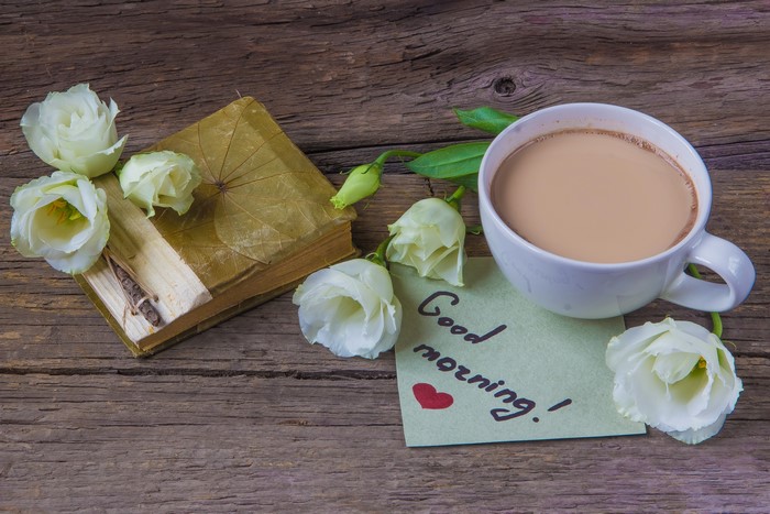 Cup of hot chocolate with white roses and a book