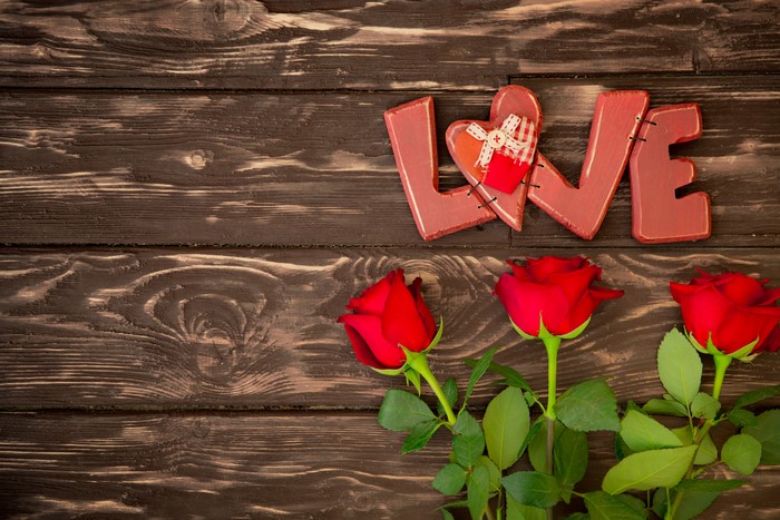 Love sign with red roses on wood planks