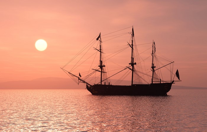 Silhouette of a sailing ship at sunset