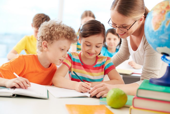 Teacher helping students with books and globe