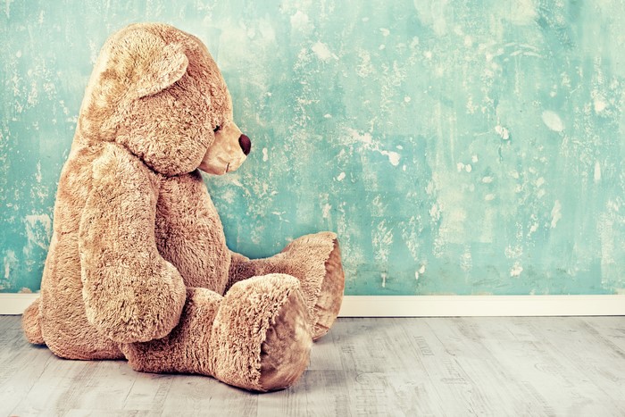 Teddy bear sitting against a textured wall