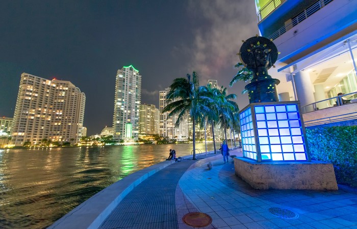 Miami skyline at night with river and sculpture