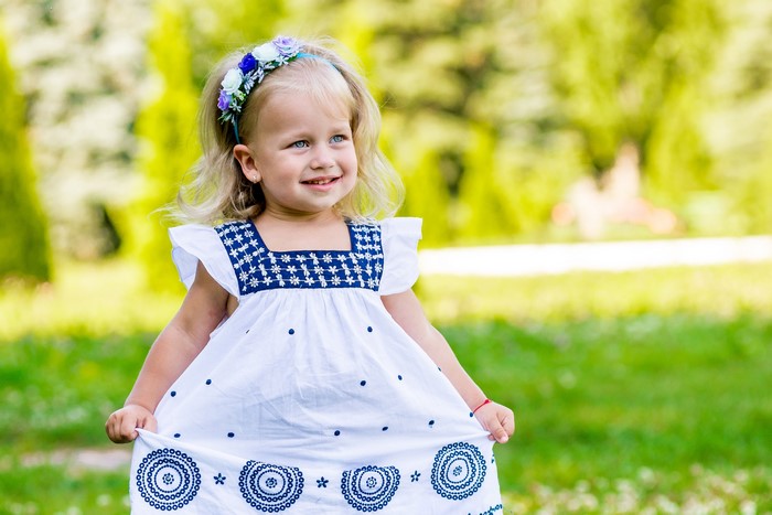 Little girl in a white dress with blue embroidery