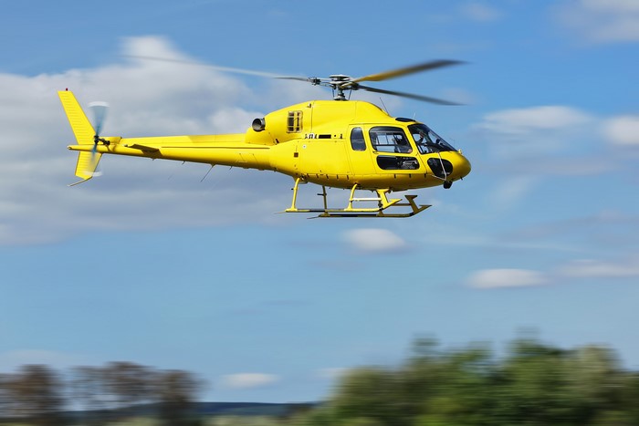 Yellow helicopter in flight against a blue sky