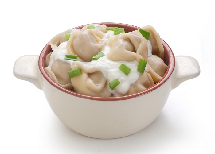 Pelmeni with sour cream and chives in a bowl