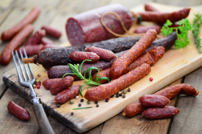Assortment of sausages on a wooden cutting board with a fork