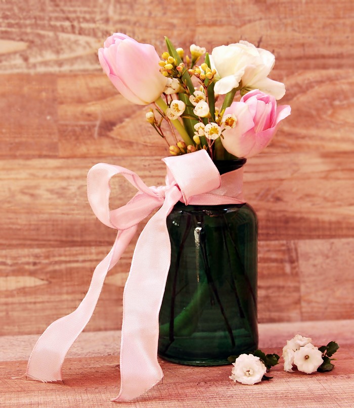 Pink and white tulips in a green vase with a pink bow
