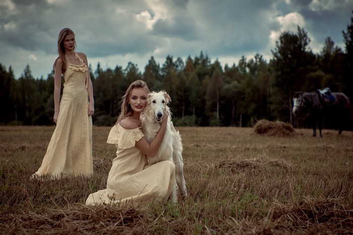 Two blonde women with a dog in a field
