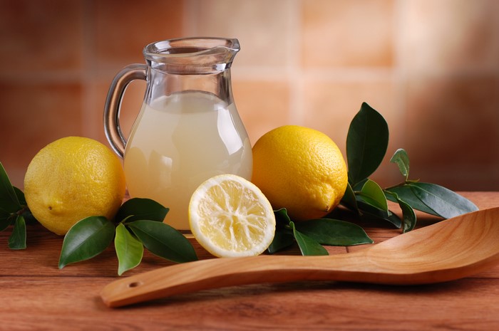 Lemons and lemonade in a jug with a spoon