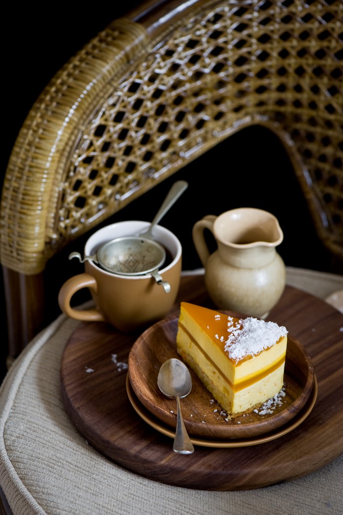 Slice of layered cake with coconut on a wooden plate