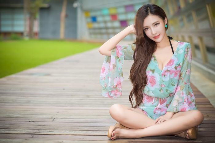 Asian Woman Sitting on Wooden Deck in Floral Outfit