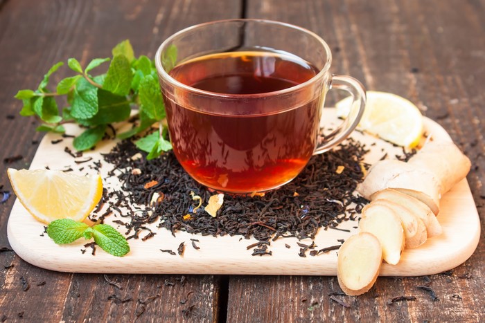 Cup of tea with ginger, lemon, and mint on a cutting board