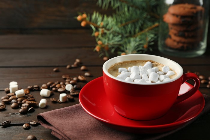 Red mug of hot chocolate with marshmallows and coffee beans