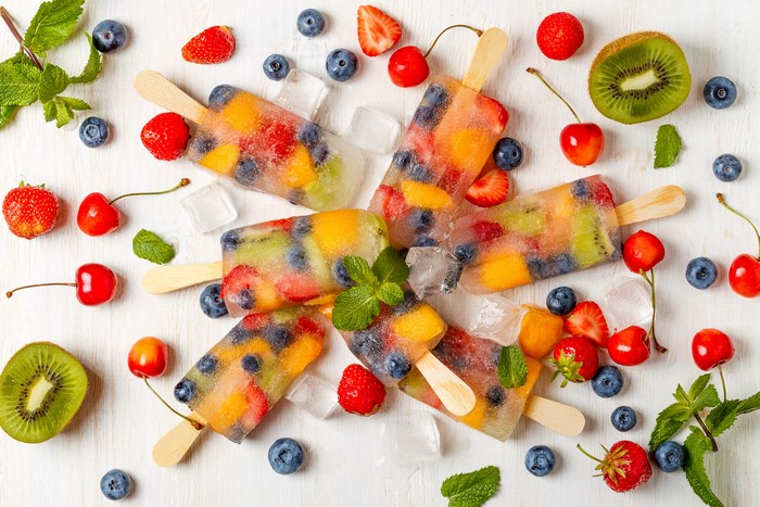 Fruit popsicles with strawberries, blueberries, kiwi, and cherries