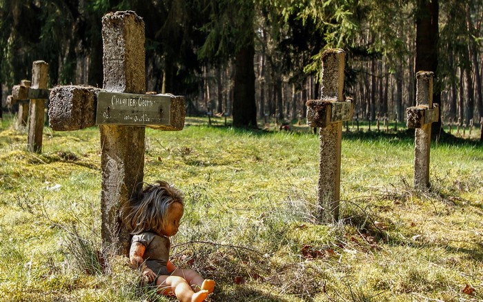 Doll in a Cemetery with Stone Crosses