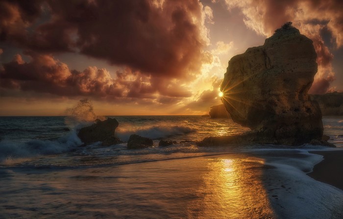 Sunset over the coast with waves crashing on rocks