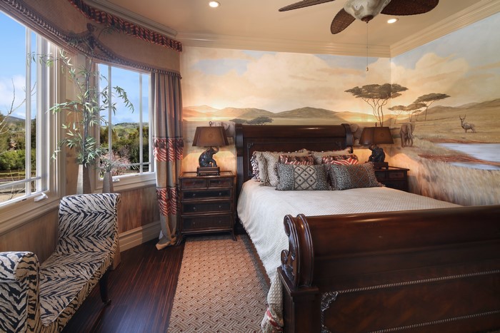 Safari themed bedroom with a large bed and mural