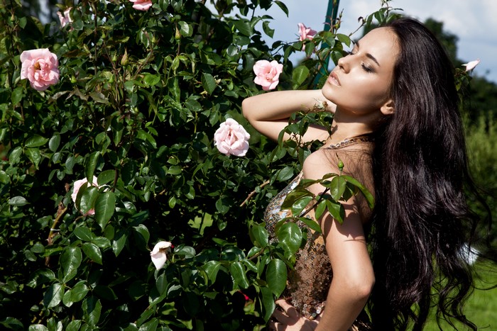 Woman with long brown hair near pink roses