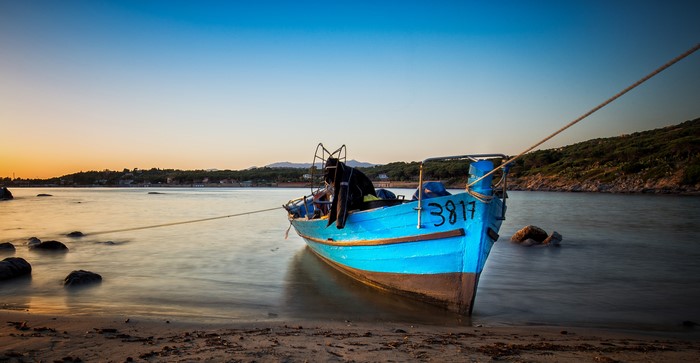 Blue boat on the coast at sunset