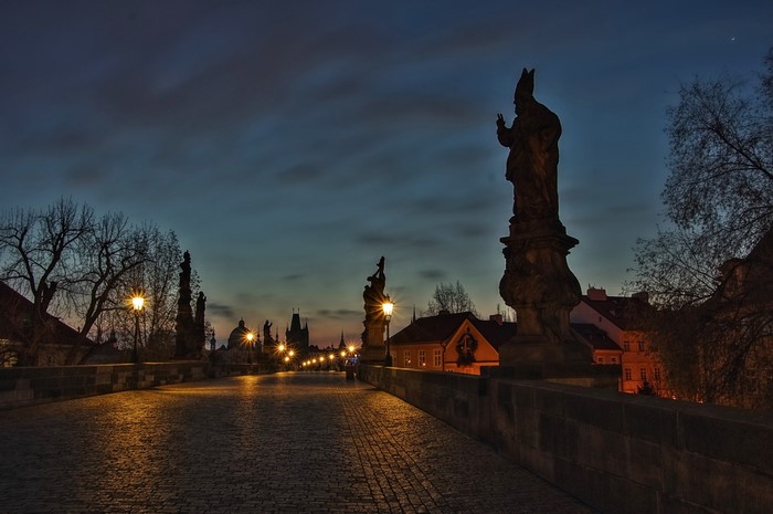Charles Bridge at night with statues and streetlights in Prague