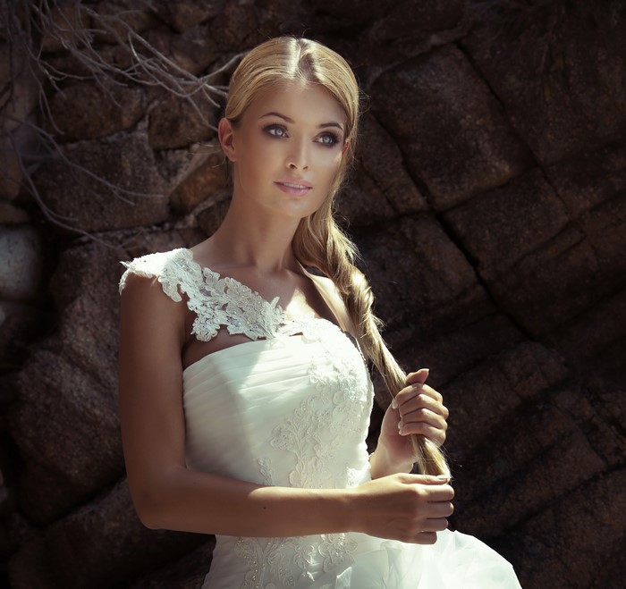 Blonde woman in wedding dress holding her braid