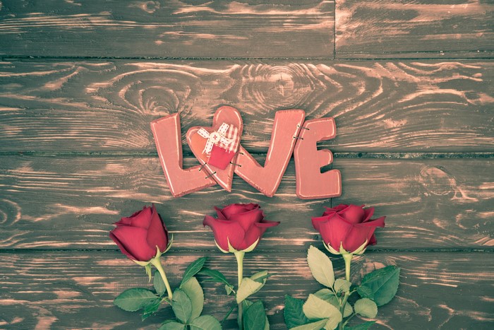 Love letters and red roses on wood planks