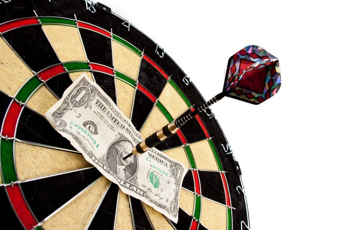 Dart hitting a one dollar bill on a dartboard