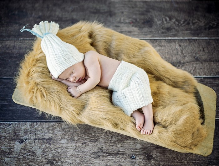 Infant sleeping on fur with winter hat